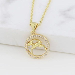 Macro detail of gold Capricorn necklace featuring a round pendant with pink zircons