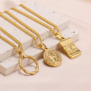 Detailed macro view of gold-plated necklaces with coin, cross, and bamboo ring pendants