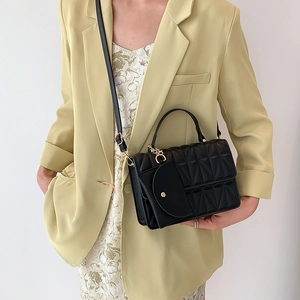 Black quilted handbag with gold hardware and mini charm pouch on shoulder strap