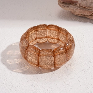 Makroaufnahme des Bernstein-Resin-Armbands mit feinen goldenen Glitzertexturen