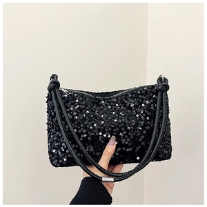 Detail view of glossy black sequins and elegant knotted shoulder strap on the baguette bag