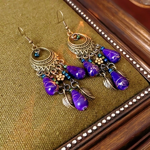 Detailed close-up of vintage bronze earrings with purple teardrop beads and floral accents