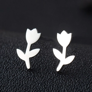 Macro shot of silver tulip-shaped stainless steel earrings on a black textured surface