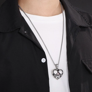 Silver heart skull pendant with red gemstone on a box chain worn by a male model