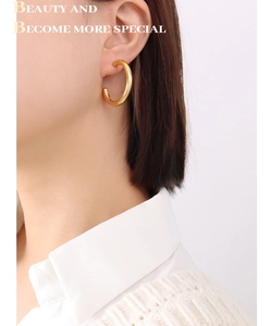 Close-up of model wearing 18K gold plated C-shaped hoop earrings in polished finish