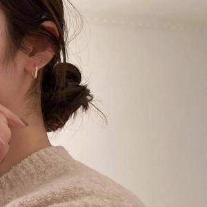 Close-up of golden textured hoop earrings on model for a minimalist aesthetic look