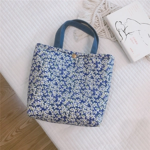 Detailed view of canvas tote bag with blue floral patterns and bronze metal snap closure