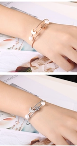 Detail of cable bangle with pearl, moon, and snowflake charms in rose gold and silver