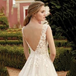 Elegant white lace wedding dress with deep V-neck and open back in a garden setting