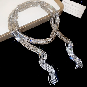 Detail shot of long rhinestone tassel necklace with brilliant silver finish on dark base
