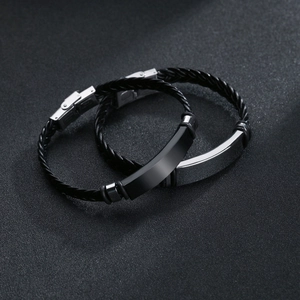 Minimalist braided leather bracelet set with stainless steel plaques on black background