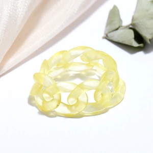 Detail of a translucent yellow resin chain ring with a matte finish on a minimalist background