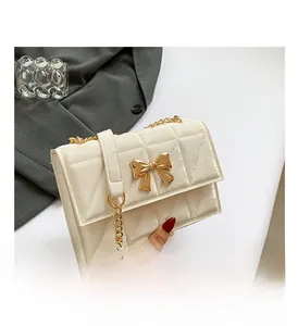 Detail der cremefarbenen Stepptasche mit goldenem Bogenschloss und Glanzleder