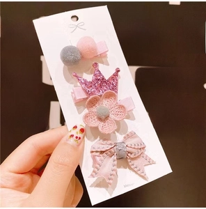 Detail of 4-piece set featuring pink crown, flower, bow, and pom pom clips for girls