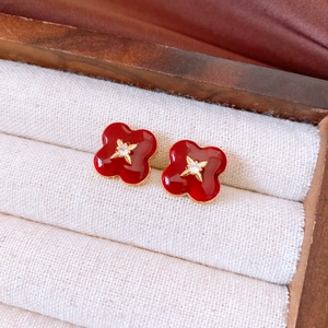 Detail of red flower stud earrings with gold trim and zircon in a jewelry box
