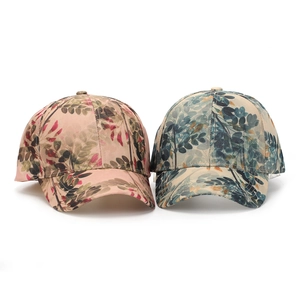 Detail view of two baseball caps featuring vibrant pink and blue floral leaf patterns