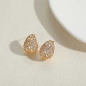 Elegant gold pear-shaped drop earrings with pavé cubic zirconia on textured background