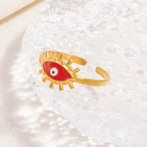Detail of 18k gold-plated evil eye ring on glass tray with water ripples decoration
