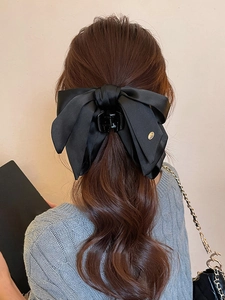 Elegant black satin bow hair claw clip styled on wavy hair for a sophisticated look