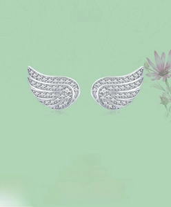 Detail of s925 silver angel wing earrings with white zircon pavé on green leaf background