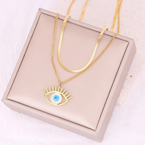 Detail of gold layered necklace featuring a blue evil eye pendant on a stone display