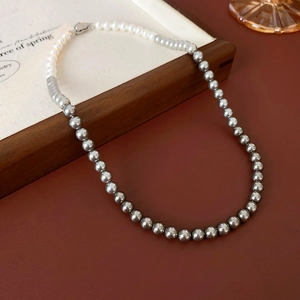 Close-up of elegant two-tone white and grey pearl necklace with metallic clasp on wood