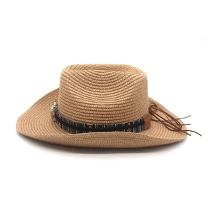 Détail d'un chapeau de cow-boy en paille avec motifs ethniques et pampilles en cuir