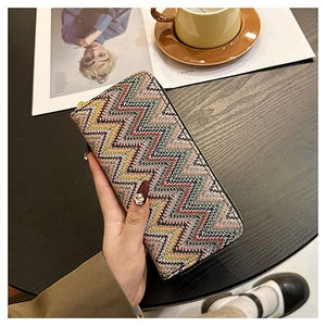 Detail of colorful woven long wallet with zipper on a wooden table in a lifestyle setting