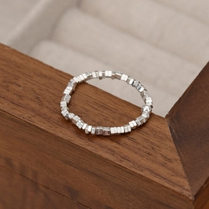 Minimalist silver square geometric ring with a central bead on a textured elastic band