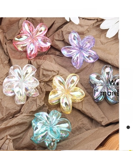 Iridescent flower hair claws in multiple colors shown on a textured brown background