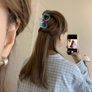 Blue heart hair claw clip with red center on model hair in a stylish mirror selfie