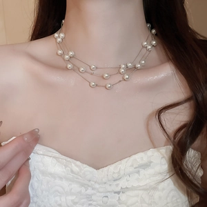 Detail of three-layer white pearl necklace with silver chains worn by model