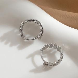 Elegant silver leaf hoop earrings with a textured vine design in a minimalist jewelry setting