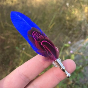 Macro detail of blue and fuchsia feather lapel pin accessory on silver metal base
