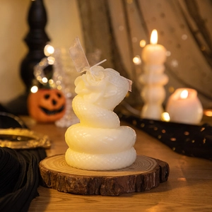 Detail of white snake and rose sculpted scented candle on a rustic wood base
