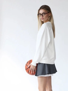 Dettaglio felpa bianca girocollo oversize con spalle scese e gonna grigia a pieghe