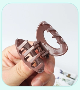 Close-up of a matte brown oval claw clip for high ponytail styling held in hand