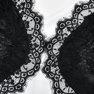 Close-up detail of black floral lace contrast stitching on white smooth fabric texture