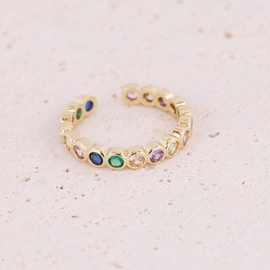 Macro shot of gold adjustable ring with multi-color zircon stones on beige stone base