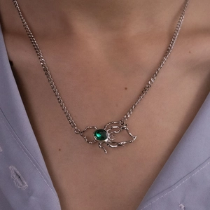 Detail shot of spider pendant necklace with green gemstone on model's neck