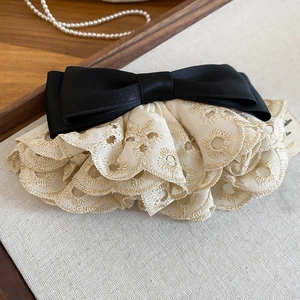 Détail de la dentelle brodée florale et du nœud en satin noir sur une pince à cheveux