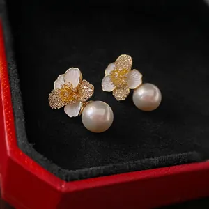Elegant floral pearl drop earrings with white enamel petals and gold accents in a luxury box