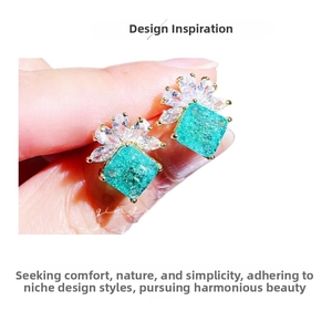 Close-up of gold stud earrings with square green stones and floral zircon accents