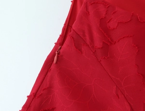 Détail de la texture jacquard rouge et fermeture éclair invisible sur la robe de soirée