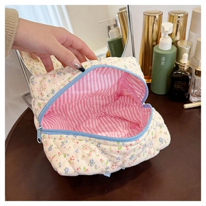 Detail of floral corduroy makeup bag featuring blue zipper and pink striped lining