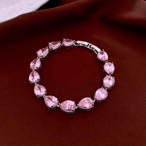 Detail of pear-shaped pink zircon bracelet with silver clasp on velvet surface