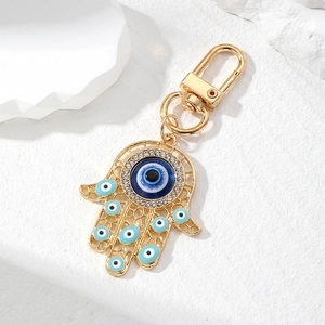 Macro shot of golden Hamsa Hand keychain with blue evil eye and sparkling rhinestones