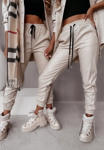 Dettaglio dei pantaloni cargo in pelle PU beige con finitura leggermente lucida e texture