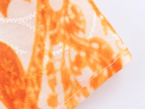Detalle de costura en zigzag y estampado tie-dye naranja en el tejido de este vestido largo