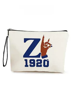 Detail of canvas pouch with durable zipper, black wrist strap and vintage graphic print